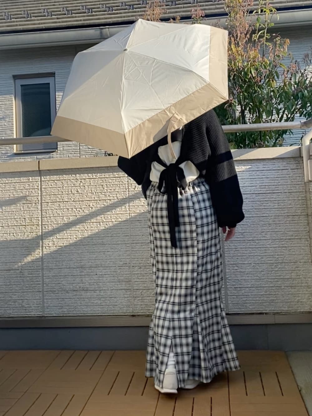 ブラック系のカーディガン/ボレロ、ホワイト系のTシャツ/カットソー、ブラック系のスカートを着用したレディースの春コーディネートの2枚目の写真
