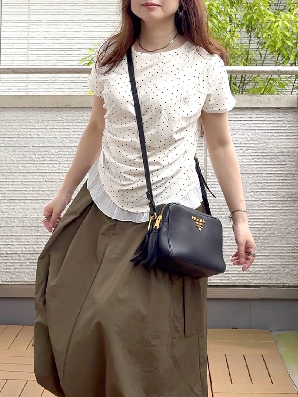 ホワイト系のTシャツ/カットソー、グリーン系のスカート、ブラック系のスニーカーを着用したレディースの春コーディネートの4枚目の写真