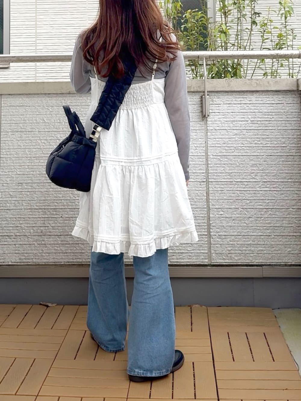 ホワイト系のワンピース、ブルー系のデニムパンツ、ブラック系のスニーカーを着用したレディースの春コーディネートの3枚目の写真