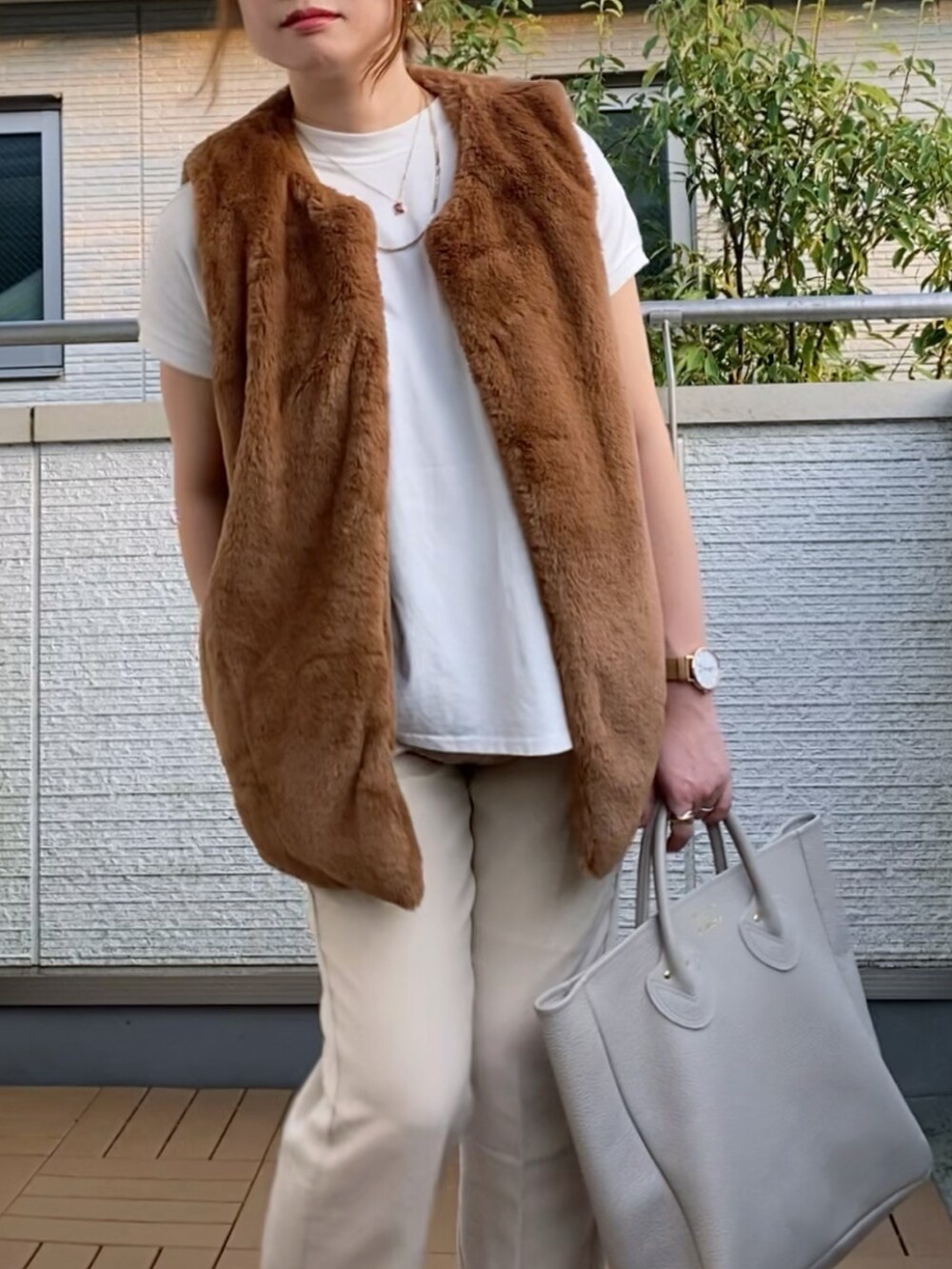 ブラウン系のベスト、ホワイト系のTシャツ/カットソー、ホワイト系のスラックスを着用したレディースの秋コーディネートの3枚目の写真