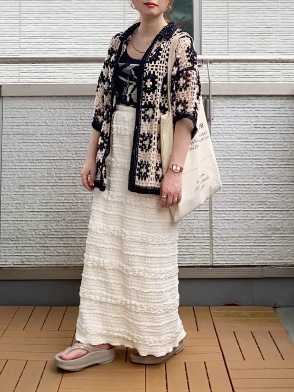 ブラック系のカーディガン/ボレロ、ホワイト系のスカート、ホワイト系のトートバッグを着用したレディースの夏コーディネートの2枚目の写真