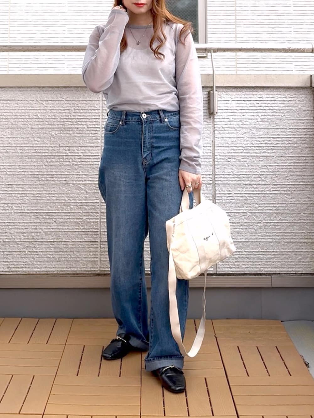 グレー系のニット/セーター、ブルー系のデニムパンツ、ホワイト系のトートバッグを着用したレディースの春コーディネートの2枚目の写真