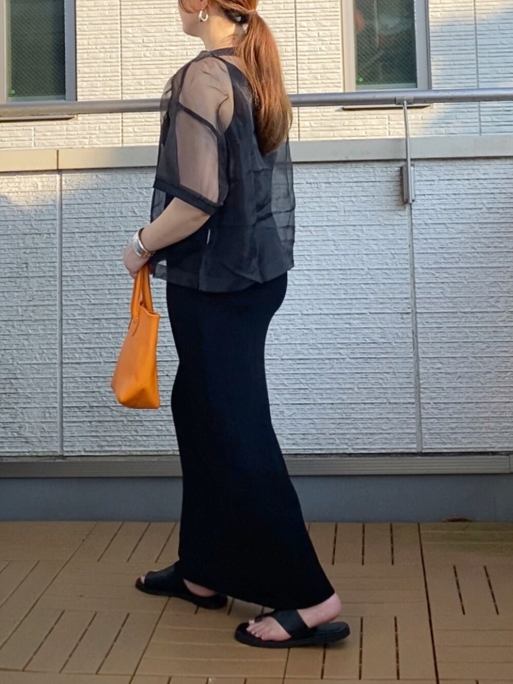 ブラック系のワンピース、ブラック系のTシャツ/カットソー、オレンジ系のトートバッグを着用したレディースの夏コーディネートの3枚目の写真
