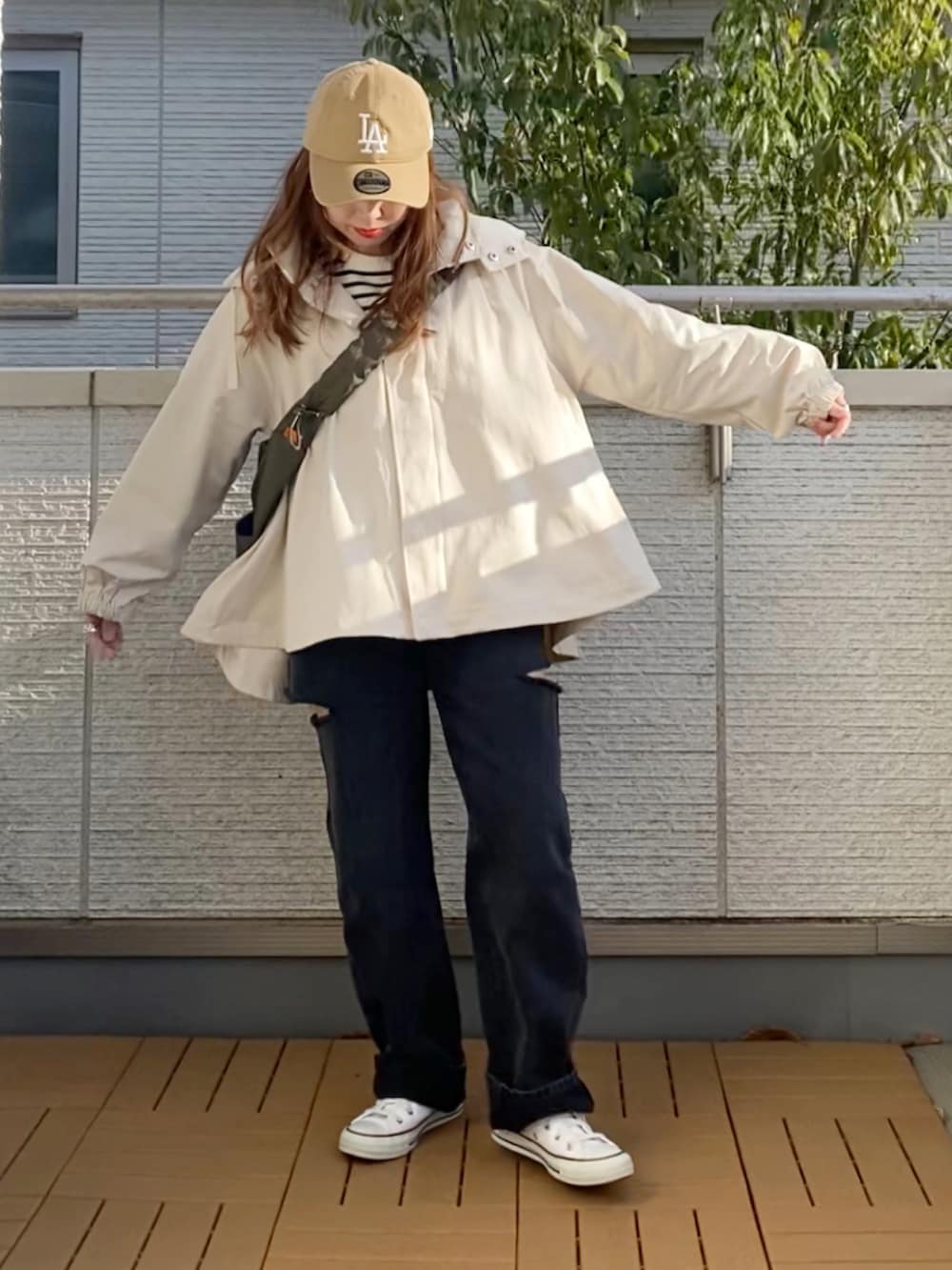 ホワイト系のマウンテンパーカー、ブラック系のTシャツ/カットソー、ブラック系のデニムパンツを着用したレディースの春コーディネートの2枚目の写真