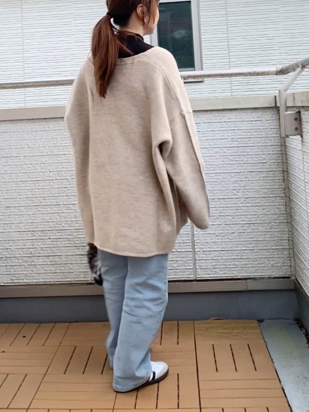 ブラック系のニット/セーター、ベージュ系のカーディガン/ボレロ、ブルー系のデニムパンツを着用したレディースの冬コーディネートの3枚目の写真