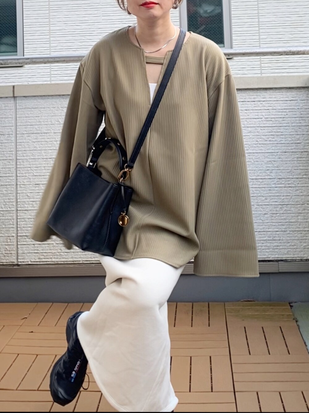 グリーン系のTシャツ/カットソー、ホワイト系のスカート、ブラック系のショルダーバッグを着用したレディースの秋コーディネートの5枚目の写真