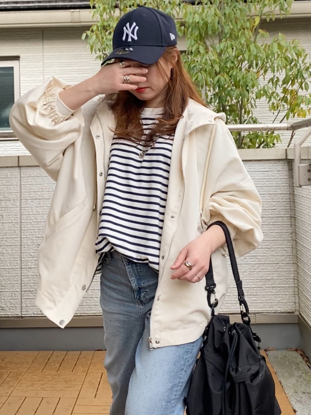 ホワイト系のマウンテンパーカー、ブラック系のTシャツ/カットソー、ブルー系のデニムパンツを着用したレディースの春コーディネートの4枚目の写真