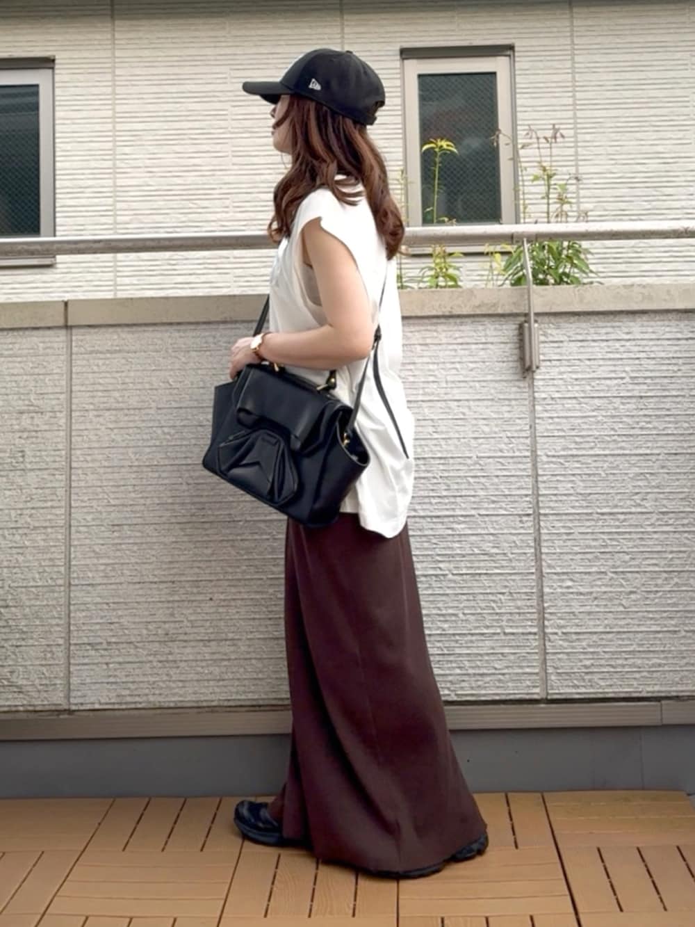 ホワイト系のTシャツ/カットソー、ブラウン系のスカート、ブラック系のハンドバッグを着用したレディースの夏コーディネートの2枚目の写真