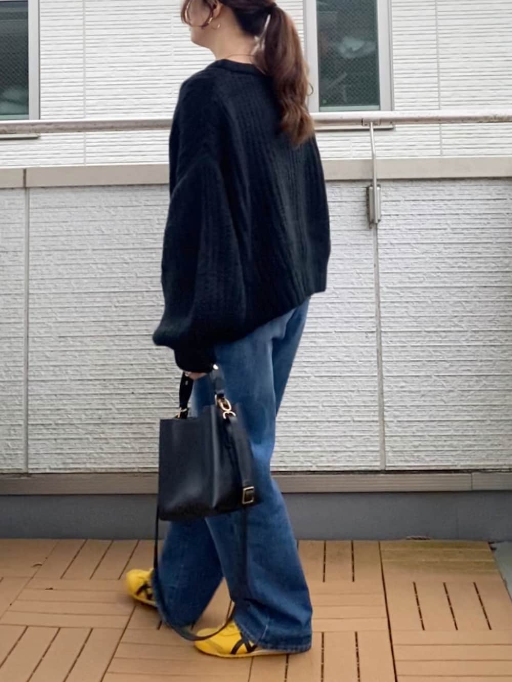 ブラック系のカーディガン/ボレロ、ブルー系のデニムパンツ、ブラック系のショルダーバッグを着用したレディースの秋コーディネートの3枚目の写真