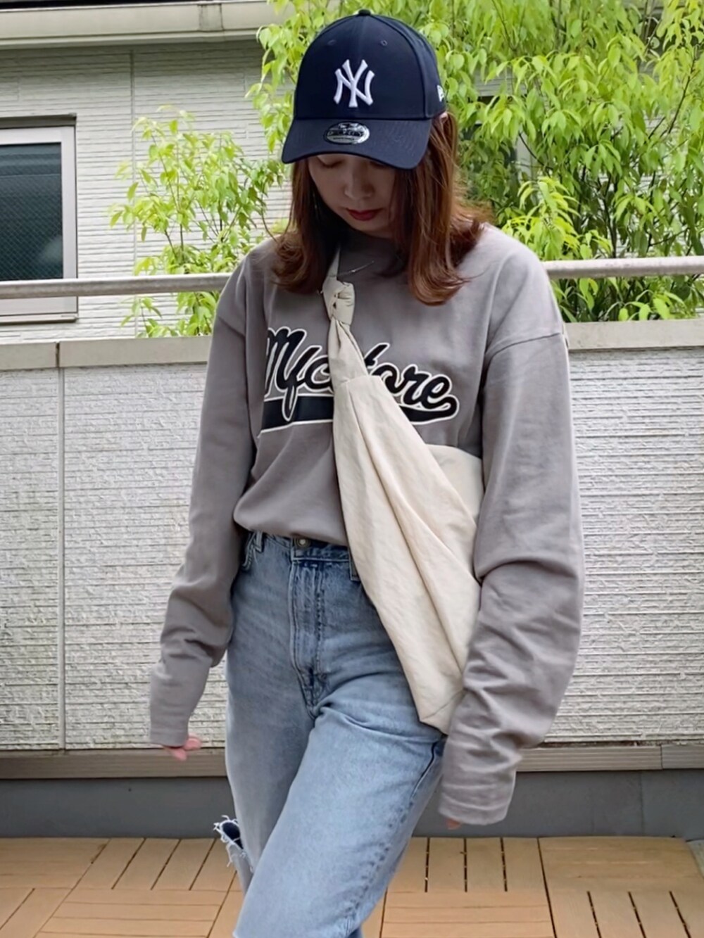 グレー系のTシャツ/カットソー、ブルー系のデニムパンツ、ホワイト系のショルダーバッグを着用したレディースの春コーディネートの3枚目の写真