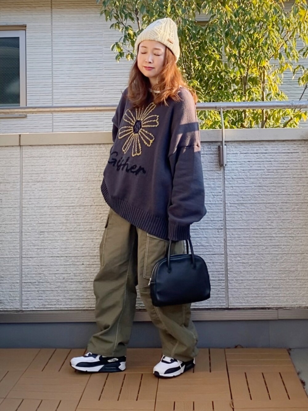 グレー系のニット/セーター、グリーン系のカーゴパンツ、ブラック系のショルダーバッグを着用したレディースの冬コーディネートの2枚目の写真