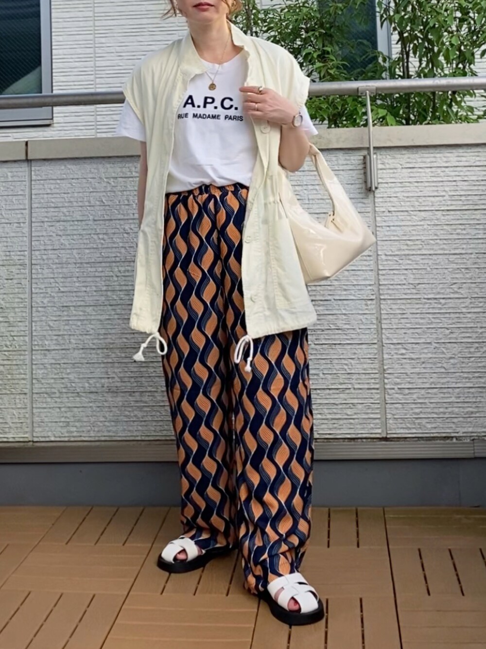 ホワイト系のベスト、ブルー系のその他パンツ、ホワイト系のハンドバッグを着用したレディースの夏コーディネートの2枚目の写真