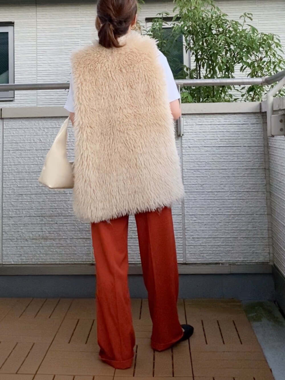 ホワイト系のベスト、ホワイト系のTシャツ/カットソー、オレンジ系のスラックスを着用したレディースの夏コーディネートの2枚目の写真