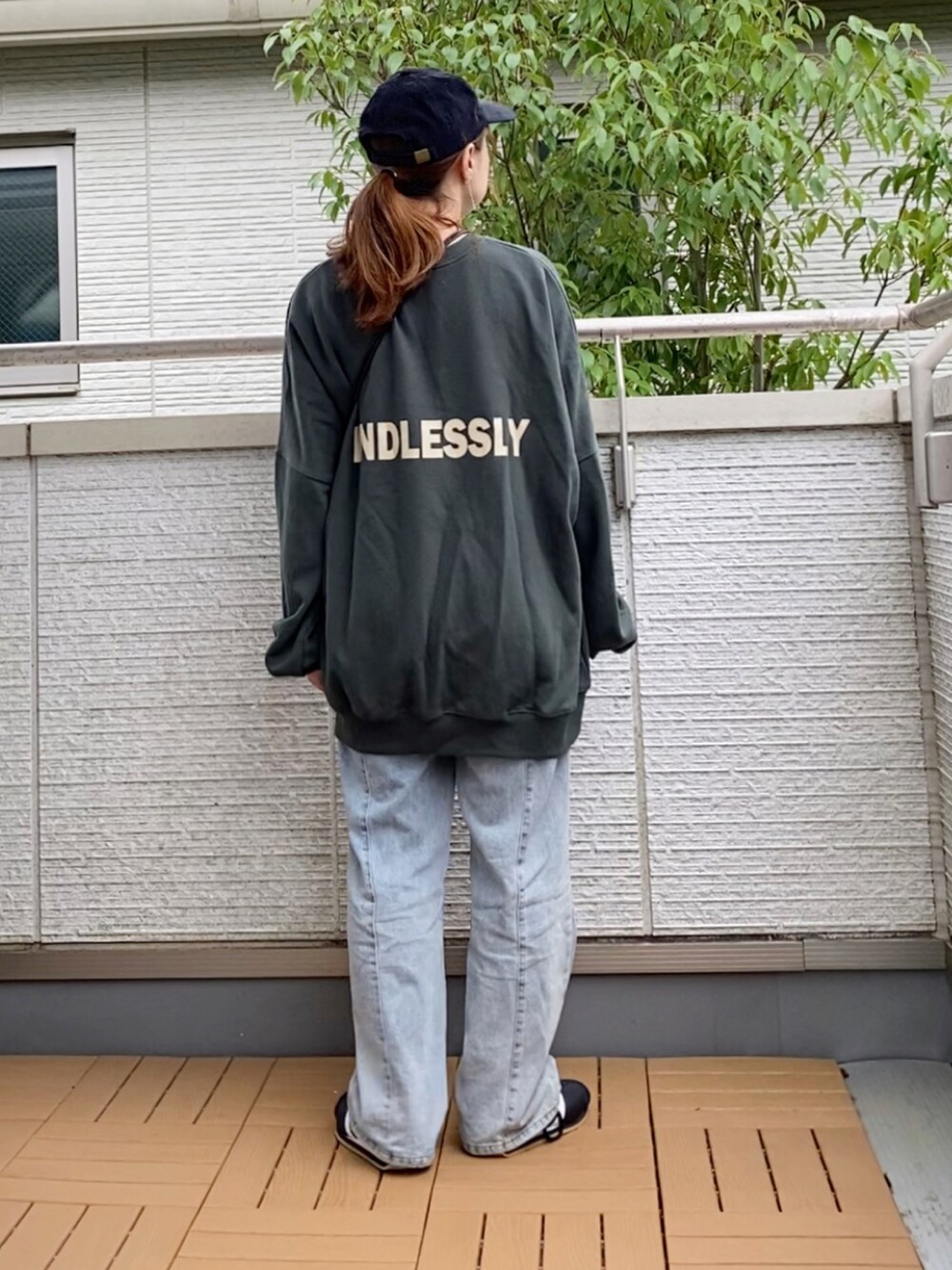 グリーン系のスウェット、ブルー系のデニムパンツ、ブラック系のショルダーバッグを着用したレディースの秋コーディネートの3枚目の写真