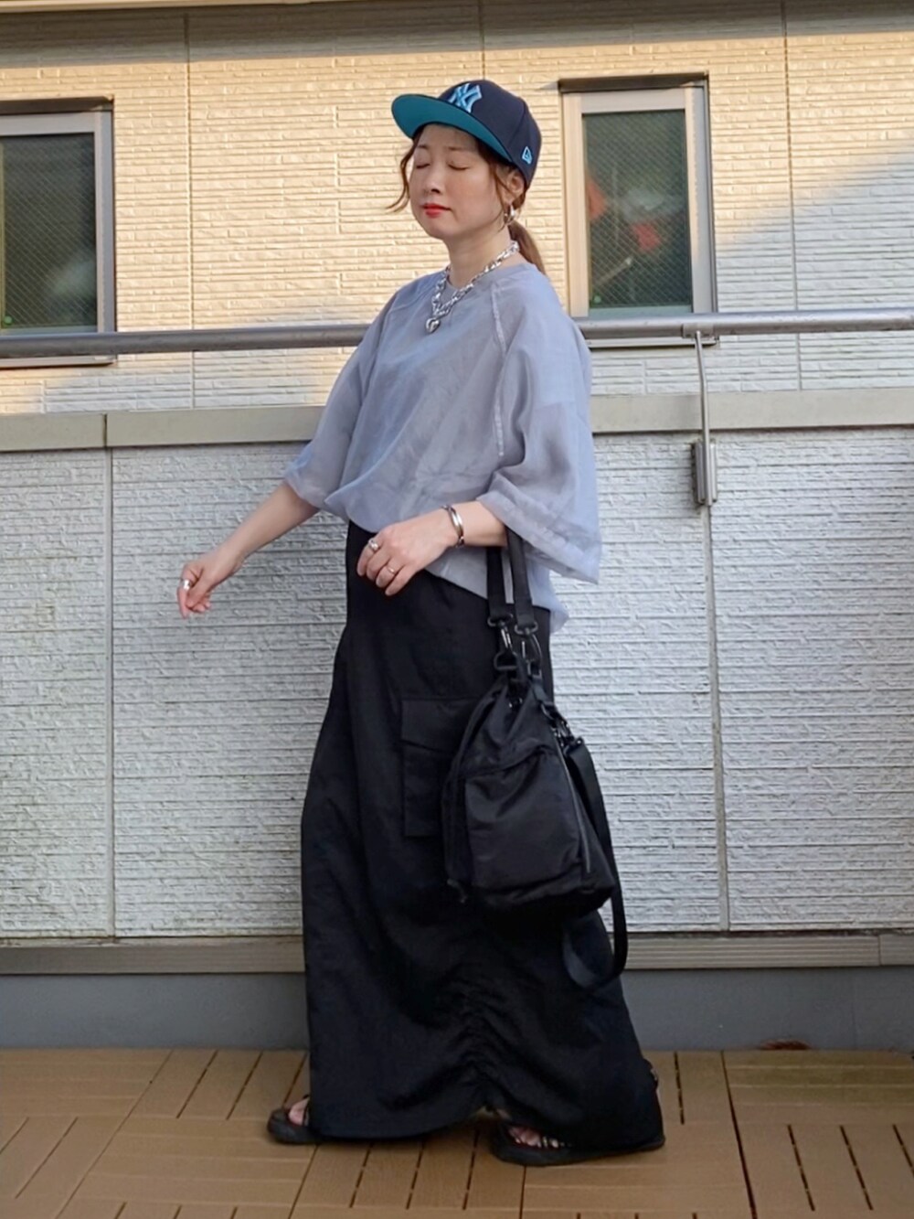 グレー系のその他トップス、ブラック系のスカート、ブラック系のショルダーバッグを着用したレディースの夏コーディネートの2枚目の写真