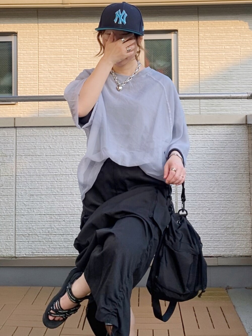 グレー系のその他トップス、ブラック系のスカート、ブラック系のショルダーバッグを着用したレディースの夏コーディネートの4枚目の写真