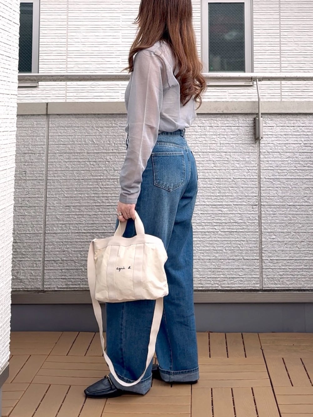 グレー系のニット/セーター、ブルー系のデニムパンツ、ホワイト系のトートバッグを着用したレディースの春コーディネートの3枚目の写真