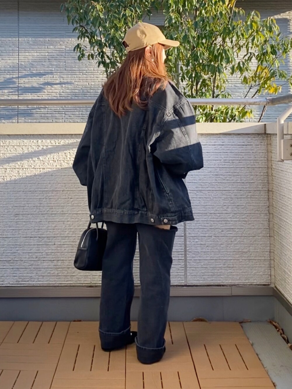 ブラック系のデニムジャケット、ホワイト系のTシャツ/カットソー、ブラック系のデニムパンツを着用したレディースの春コーディネートの2枚目の写真