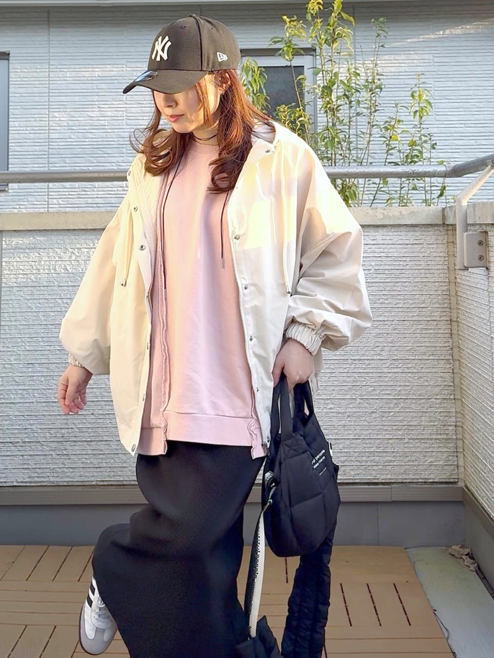 ピンク系のスウェット、ホワイト系のマウンテンパーカー、ブラック系のスカートを着用したレディースの春コーディネートの4枚目の写真