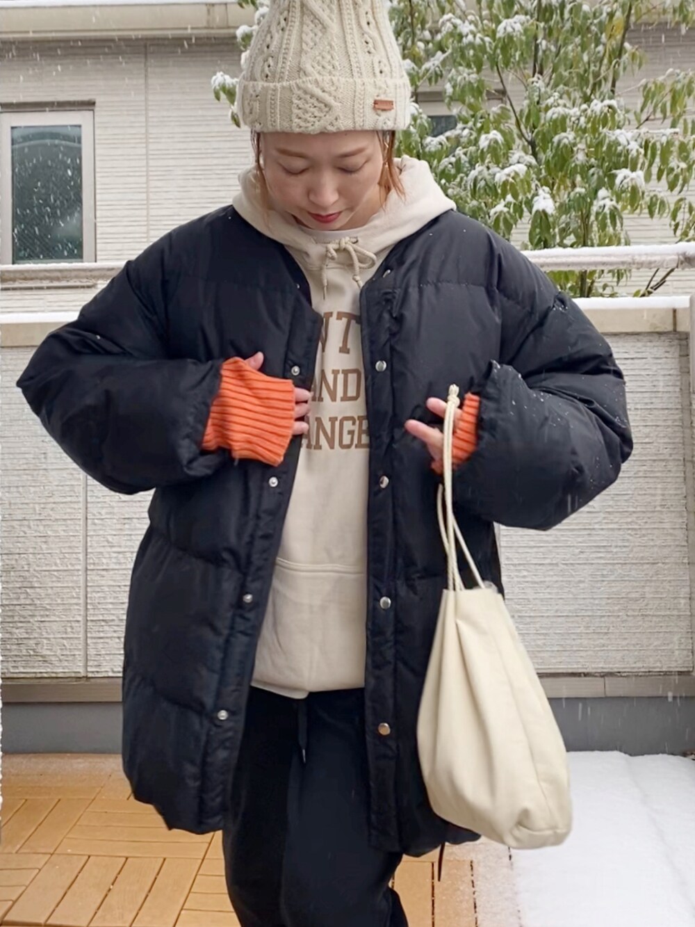 ブラック系のダウンジャケット/コート、ブラック系のその他パンツ、オレンジ系のスニーカーを着用したレディースの冬コーディネートの3枚目の写真