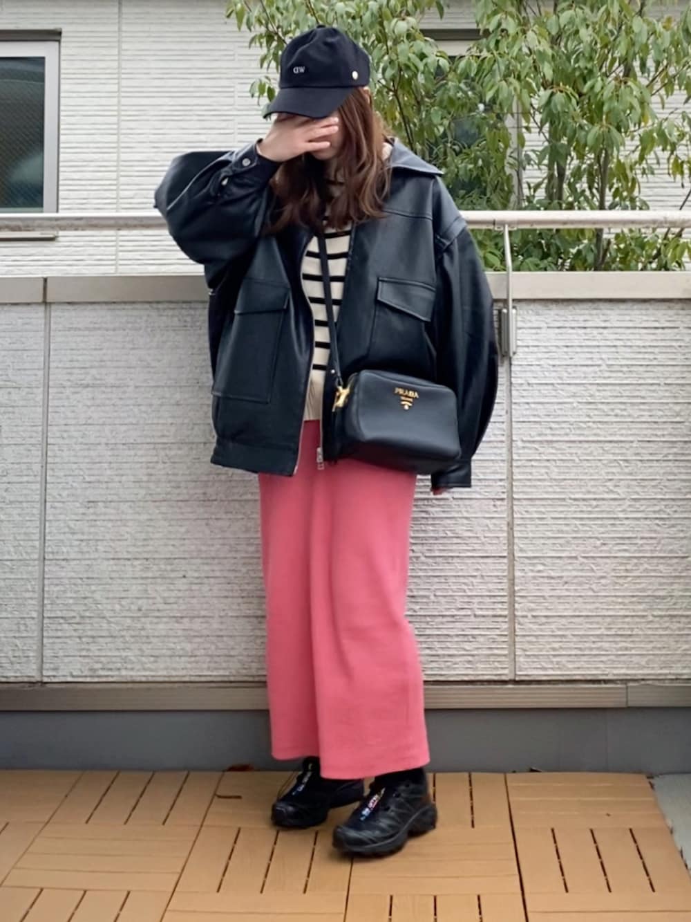 ブラック系のライダースジャケット、ホワイト系のニット/セーター、ピンク系のスカートを着用したレディースの春コーディネートの2枚目の写真