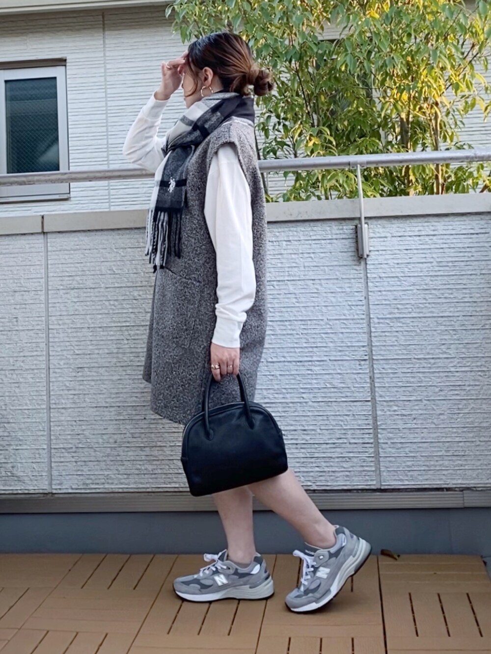 グレー系のジャンパースカート、グレー系のスニーカー、ブラック系のショルダーバッグを着用したレディースの秋コーディネートの3枚目の写真