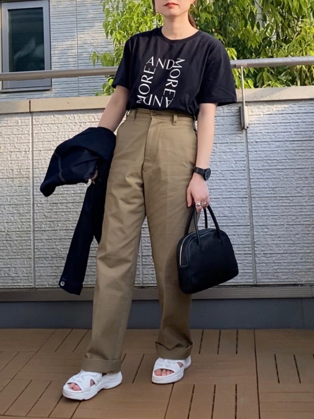 ブラック系のTシャツ/カットソー、ベージュ系のチノパンツ、ブラック系のショルダーバッグを着用したレディースの春コーディネートの2枚目の写真