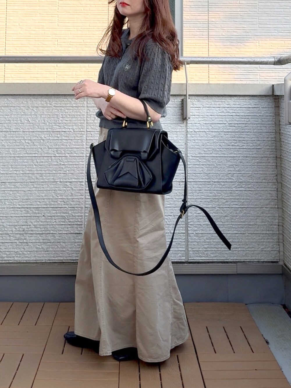 グレー系のニット/セーター、ベージュ系のスカート、ブラック系のハンドバッグを着用したレディースの春コーディネートの2枚目の写真