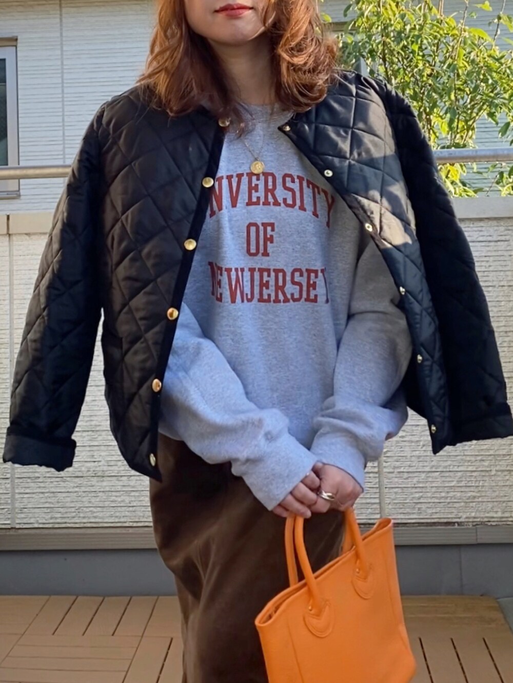 グレー系のスウェット、ブラック系のノーカラージャケット、ブラウン系のスカートを着用したレディースの秋コーディネートの2枚目の写真