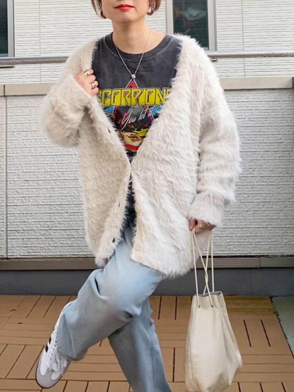 ホワイト系のカーディガン/ボレロ、ブラック系のTシャツ/カットソー、ブルー系のデニムパンツを着用したレディースの秋コーディネートの4枚目の写真