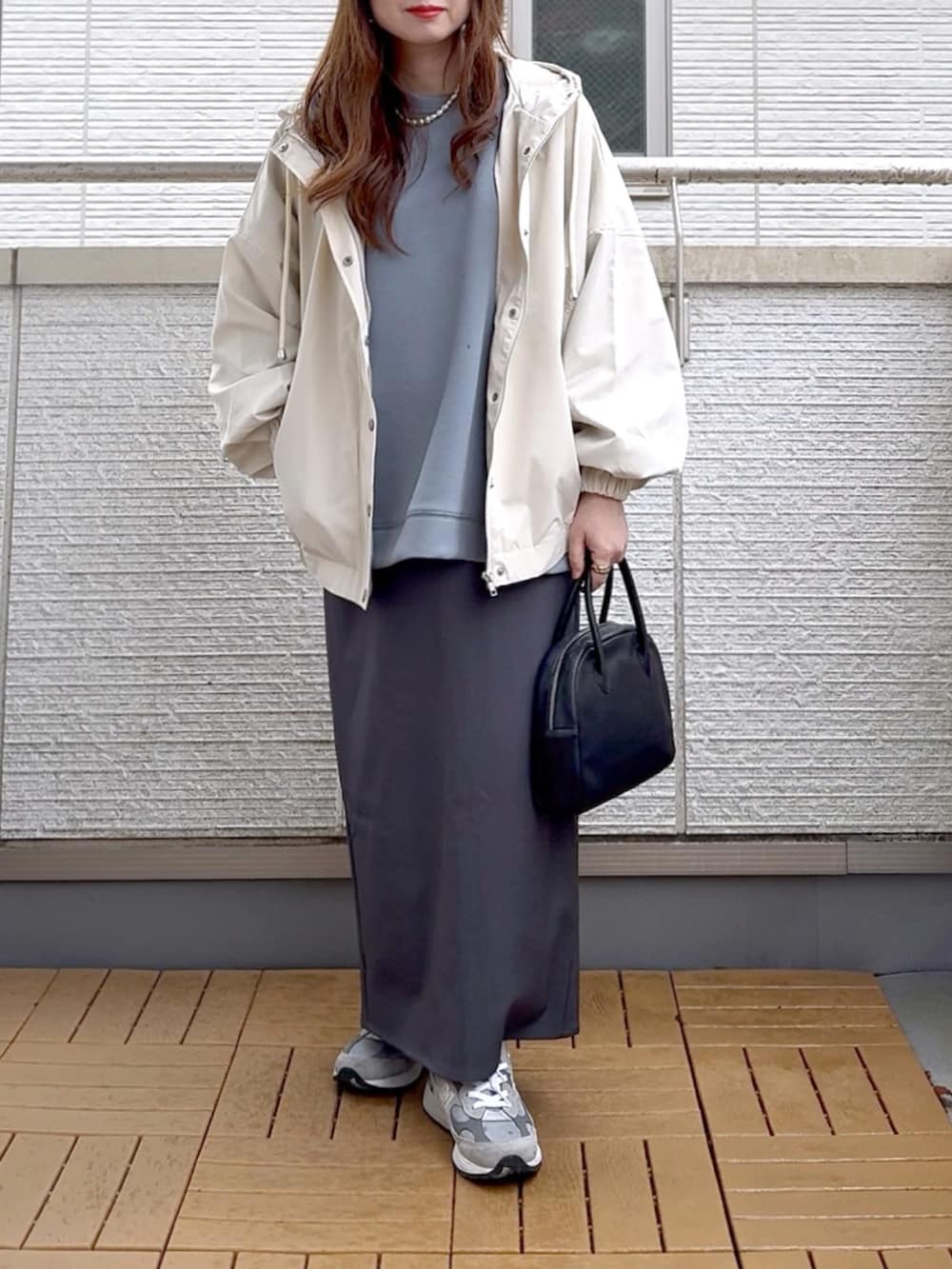 ホワイト系のマウンテンパーカー、ブルー系のスウェット、グレー系のスカートを着用したレディースの春コーディネートの2枚目の写真
