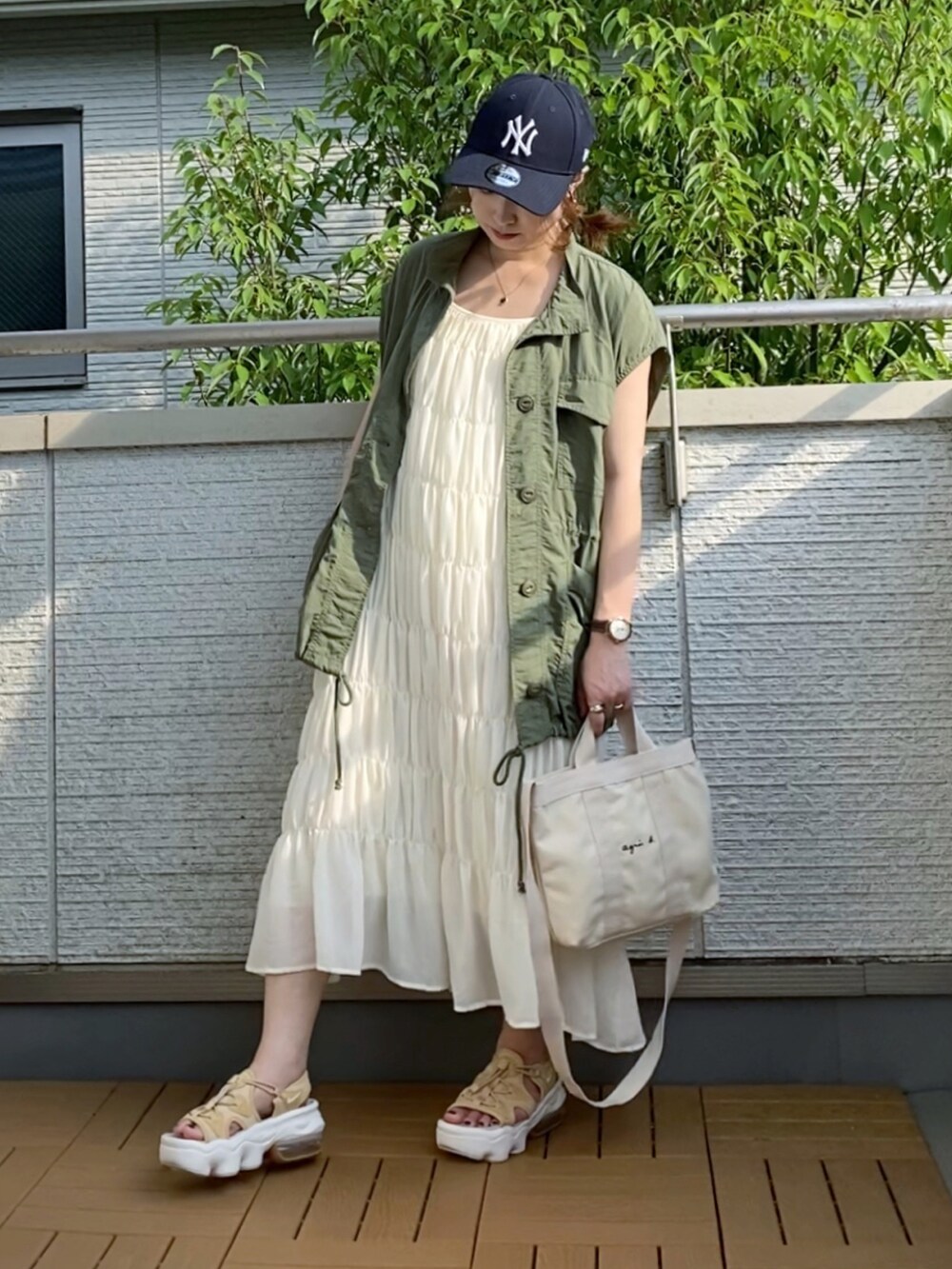 グリーン系のベスト、ホワイト系のワンピース、ホワイト系のトートバッグを着用したレディースの夏コーディネートの2枚目の写真