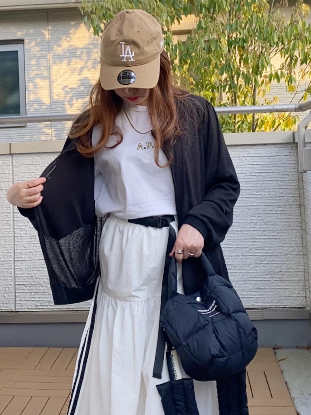 ブラック系のブルゾン、イエロー系のTシャツ/カットソー、ホワイト系のスカートを着用したレディースの春コーディネートの5枚目の写真