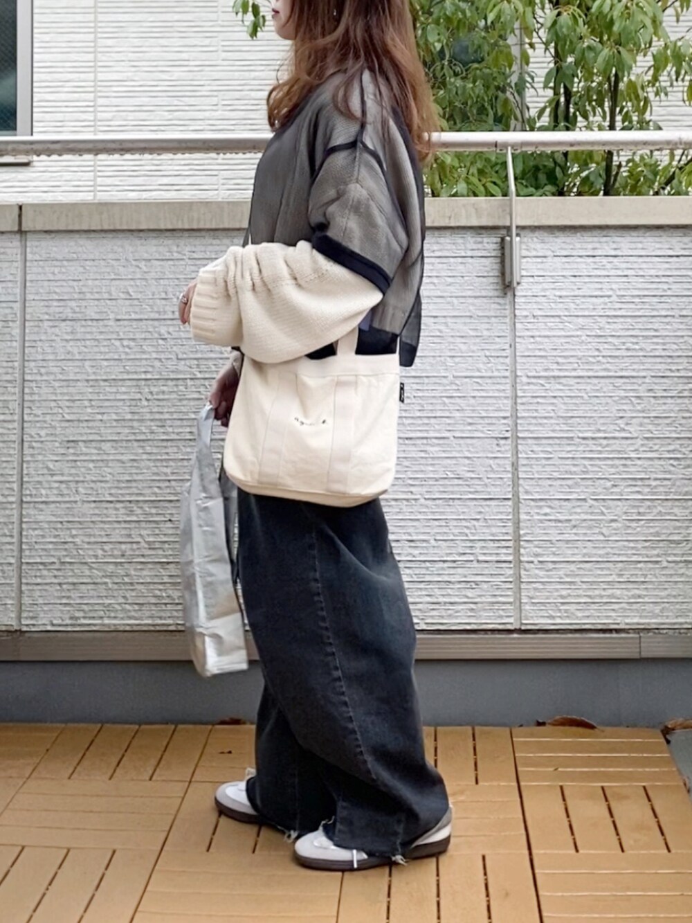 ブラック系のTシャツ/カットソー、ホワイト系のニット/セーター、ブラック系のデニムパンツを着用したレディースの春コーディネートの3枚目の写真