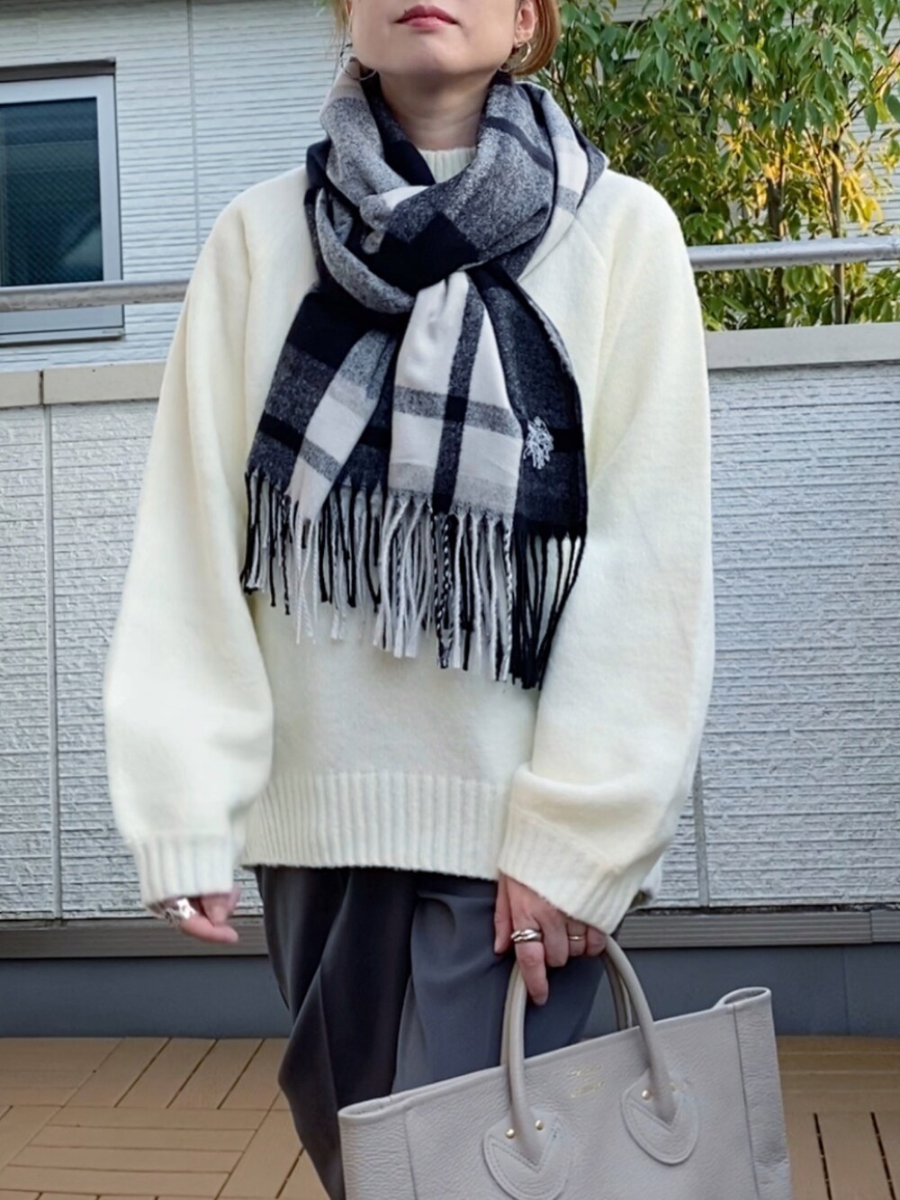 ホワイト系のニット/セーター、グレー系のスラックス、ベージュ系のトートバッグを着用したレディースの秋コーディネートの3枚目の写真