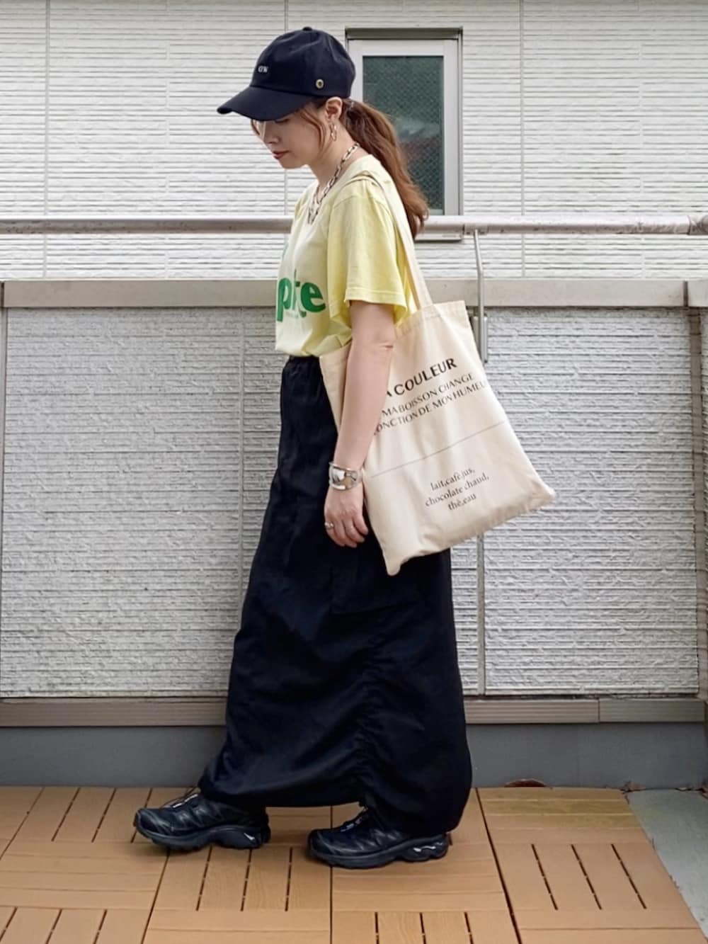 イエロー系のTシャツ/カットソー、ブラック系のスカート、ホワイト系のトートバッグを着用したレディースの夏コーディネートの2枚目の写真