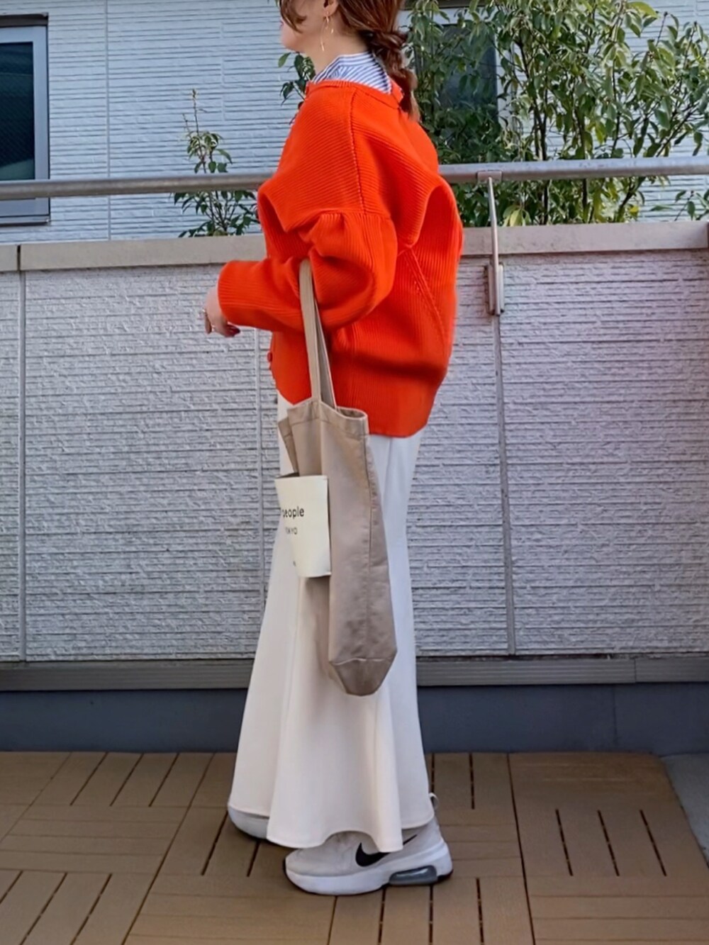 オレンジ系のカーディガン/ボレロ、ブルー系のシャツ/ブラウス、ホワイト系のスカートを着用したレディースの春コーディネートの3枚目の写真