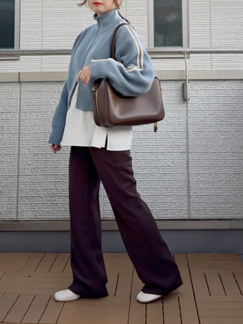 ブルー系のニット/セーター、ホワイト系のシャツ/ブラウス、ブラウン系のスラックスを着用したレディースの冬コーディネートの2枚目の写真