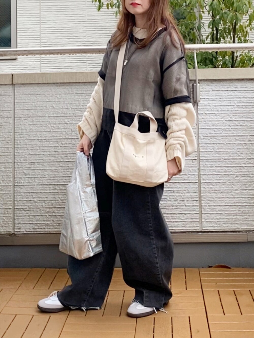 ブラック系のTシャツ/カットソー、ホワイト系のニット/セーター、ブラック系のデニムパンツを着用したレディースの春コーディネートの2枚目の写真