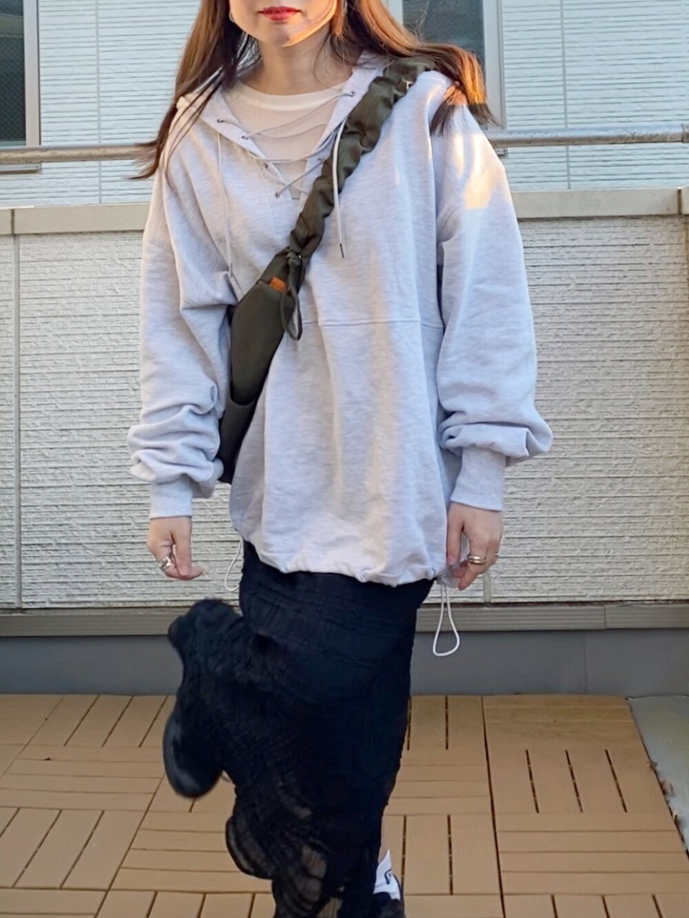 グレー系のパーカー、ブラック系のスカート、グリーン系のショルダーバッグを着用したレディースの冬コーディネートの4枚目の写真