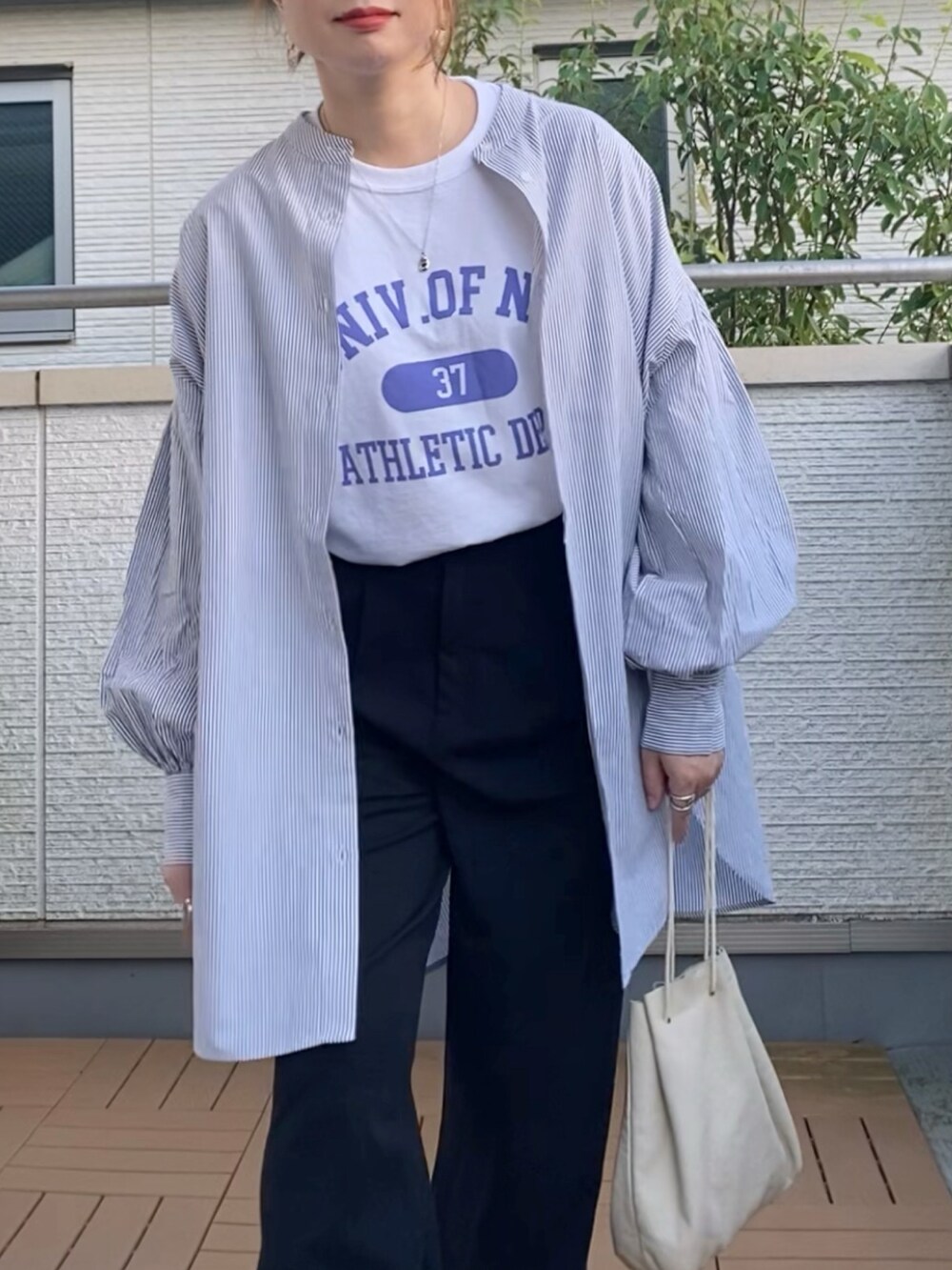 ホワイト系のTシャツ/カットソー、ブラック系のシャツ/ブラウス、ブラック系のスラックスを着用したレディースの秋コーディネートの2枚目の写真