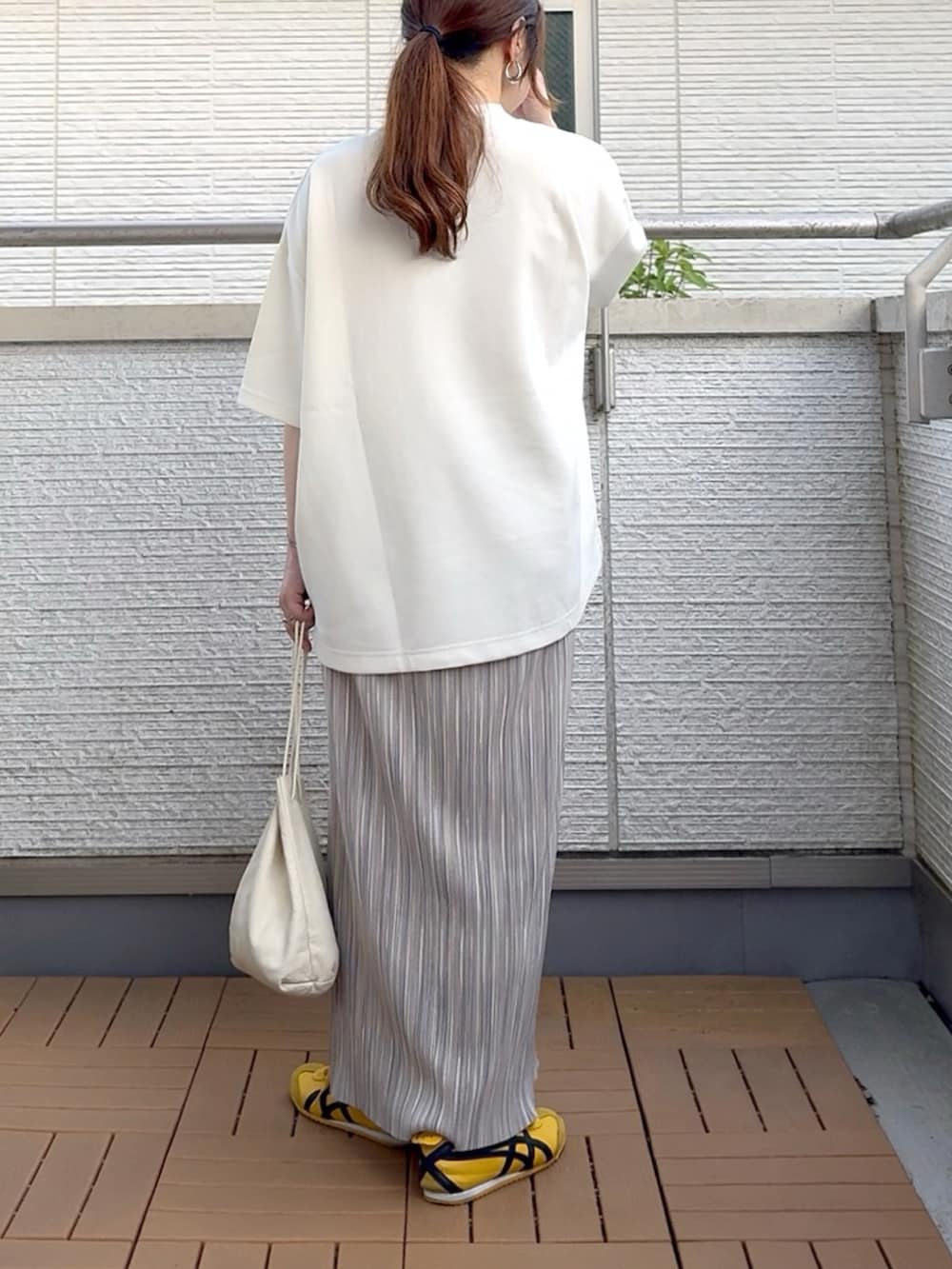 グレー系のスカート、ホワイト系のTシャツ/カットソー、イエロー系のスニーカーを着用したレディースの夏コーディネートの4枚目の写真