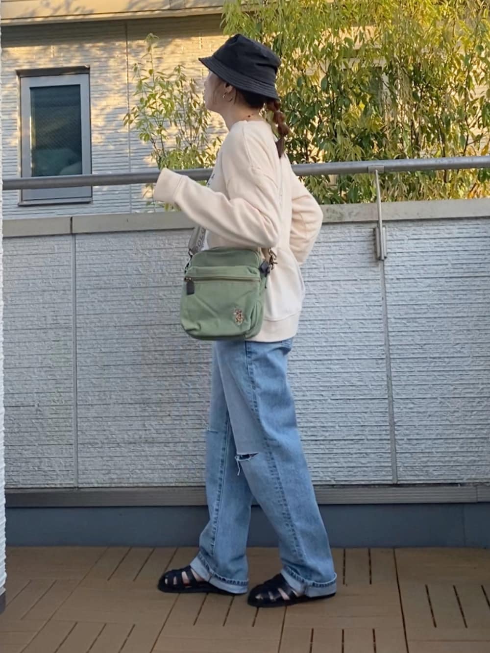 ホワイト系のスウェット、ブルー系のデニムパンツ、グリーン系のショルダーバッグを着用したレディースの春コーディネートの2枚目の写真