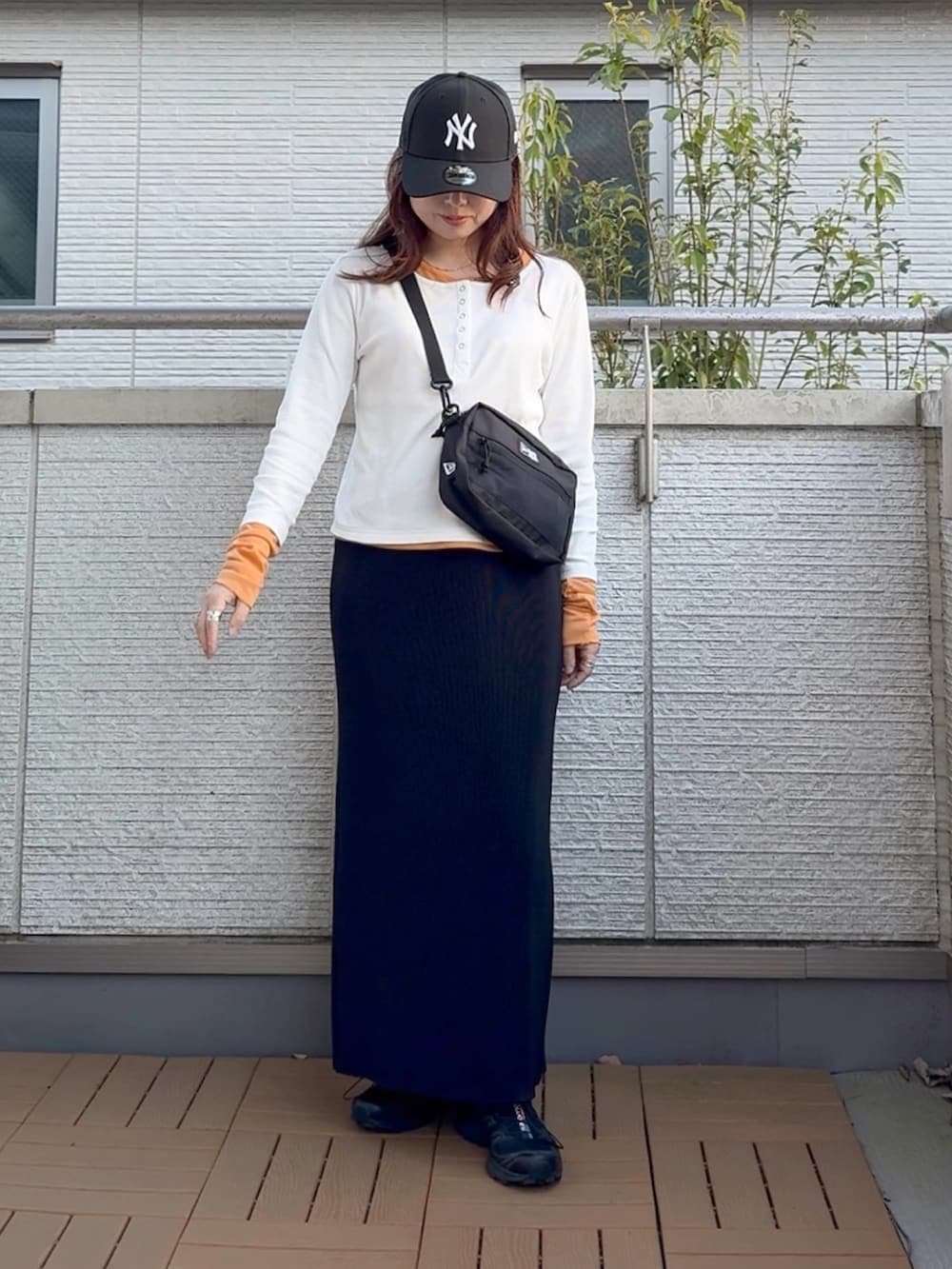 ブラック系のスカート、ホワイト系のTシャツ/カットソー、ブラック系のショルダーバッグを着用したレディースの春コーディネートの2枚目の写真
