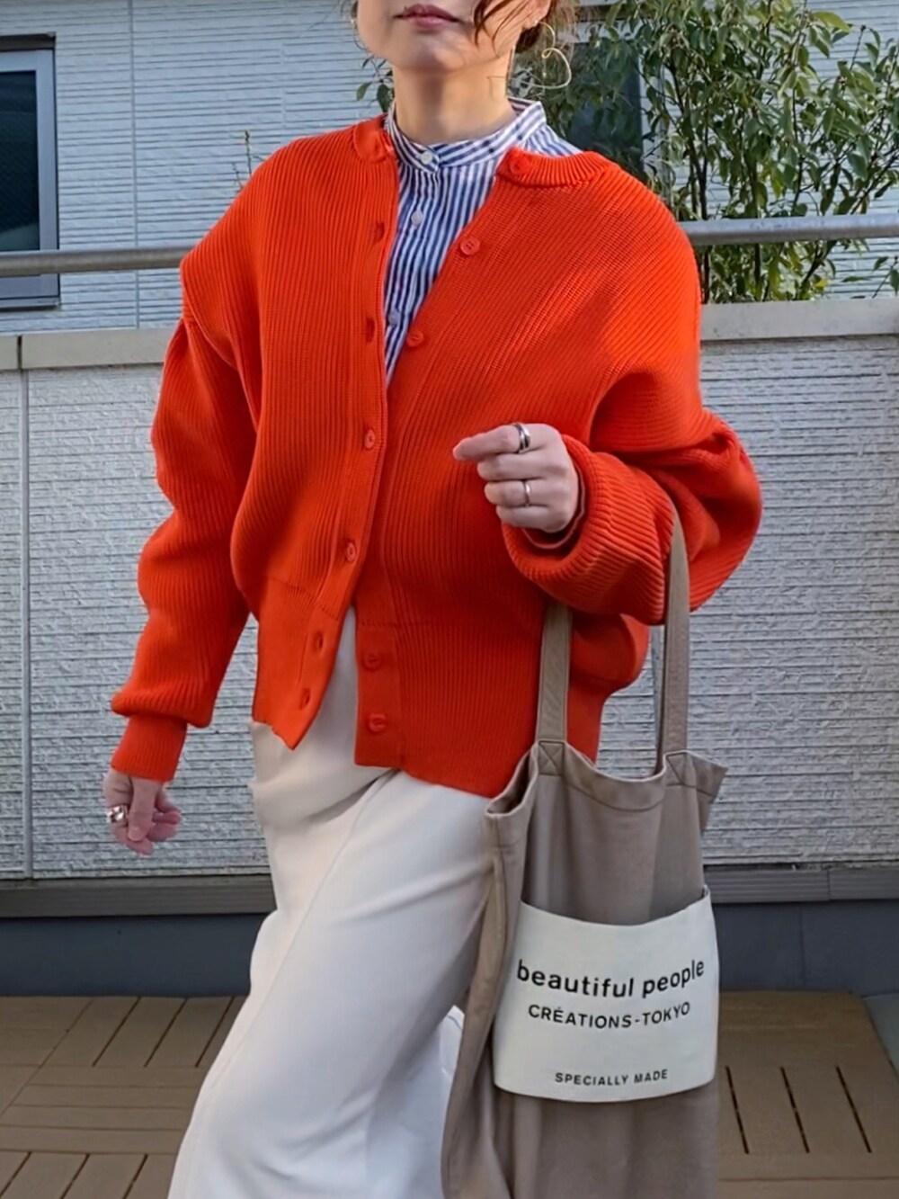 オレンジ系のカーディガン/ボレロ、ブルー系のシャツ/ブラウス、ホワイト系のスカートを着用したレディースの春コーディネートの2枚目の写真