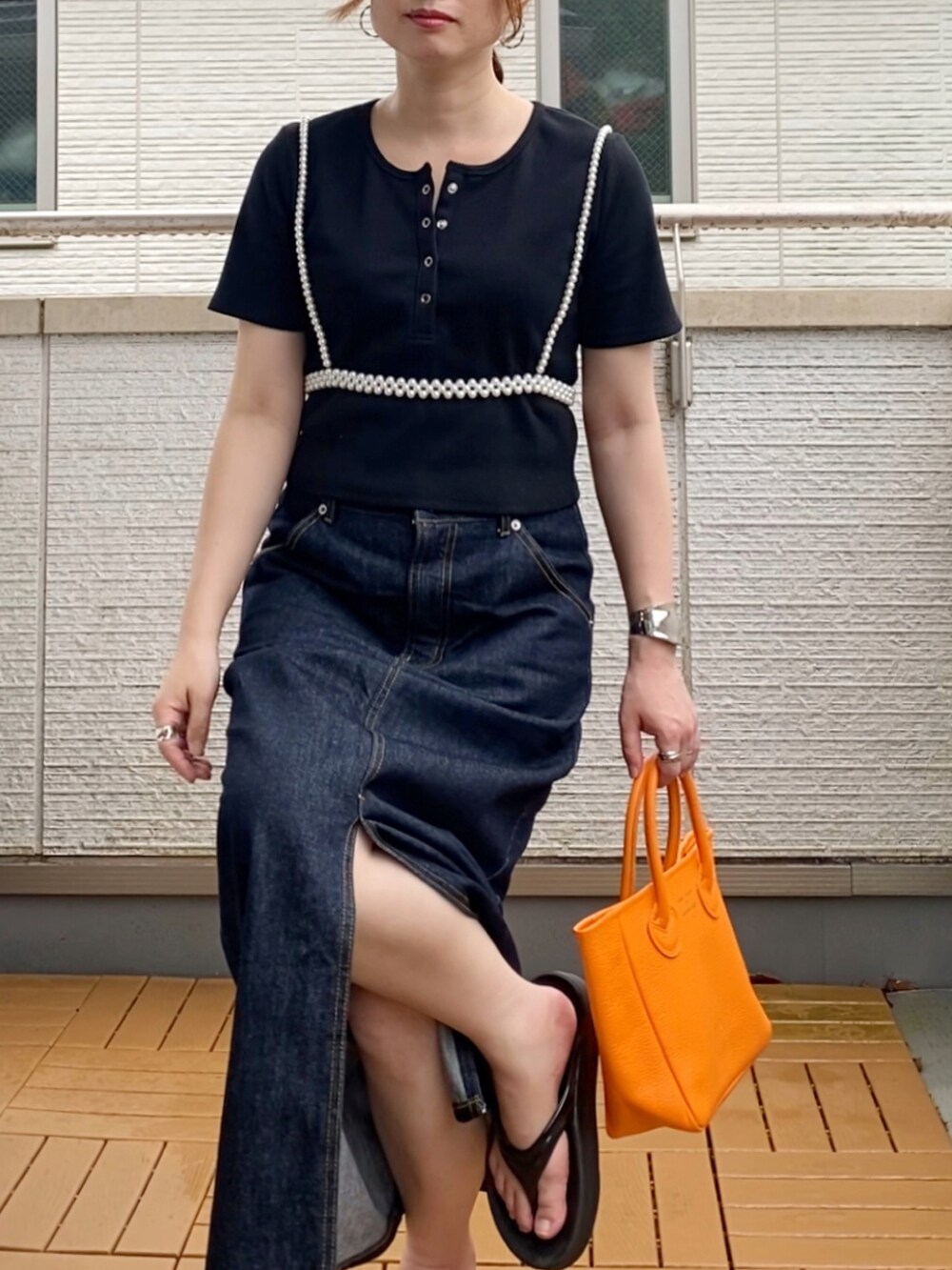 ブラック系のTシャツ/カットソー、ブルー系のデニムスカート、オレンジ系のトートバッグを着用したレディースの夏コーディネートの4枚目の写真