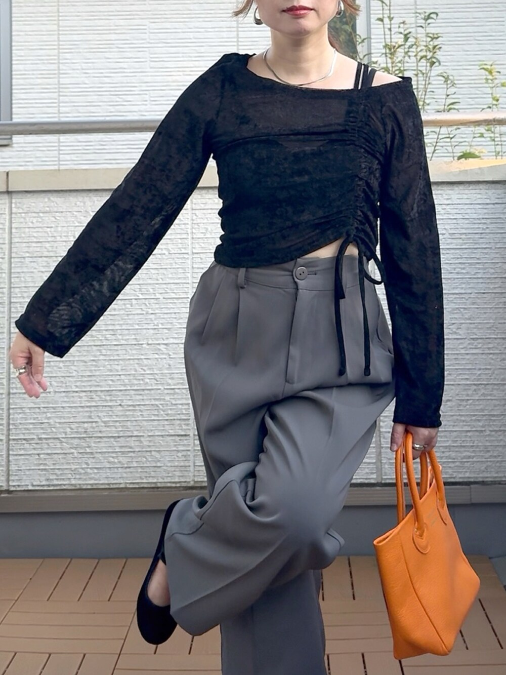 ブラック系のTシャツ/カットソー、グレー系のスラックス、オレンジ系のトートバッグを着用したレディースの秋コーディネートの3枚目の写真