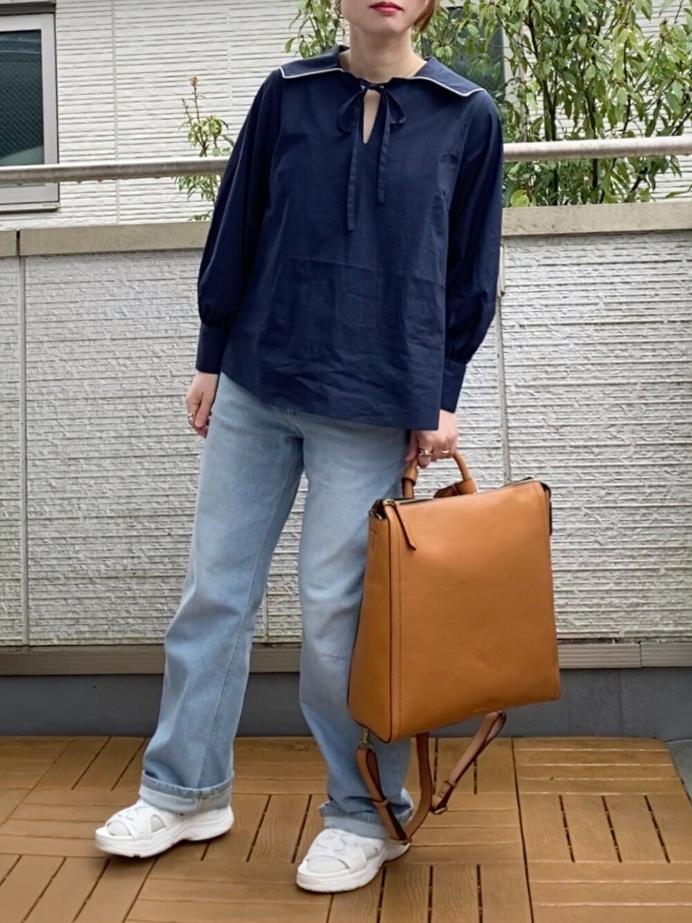 ブルー系のシャツ/ブラウス、ブルー系のデニムパンツ、イエロー系のバックパック/リュックを着用したレディースの春コーディネートの2枚目の写真