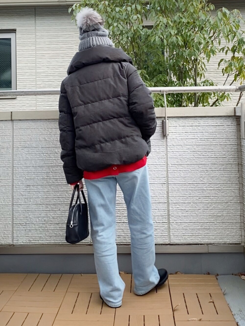 グレー系のダウンジャケット/コート、レッド系のカーディガン/ボレロ、ブルー系のデニムパンツを着用したレディースの冬コーディネートの3枚目の写真