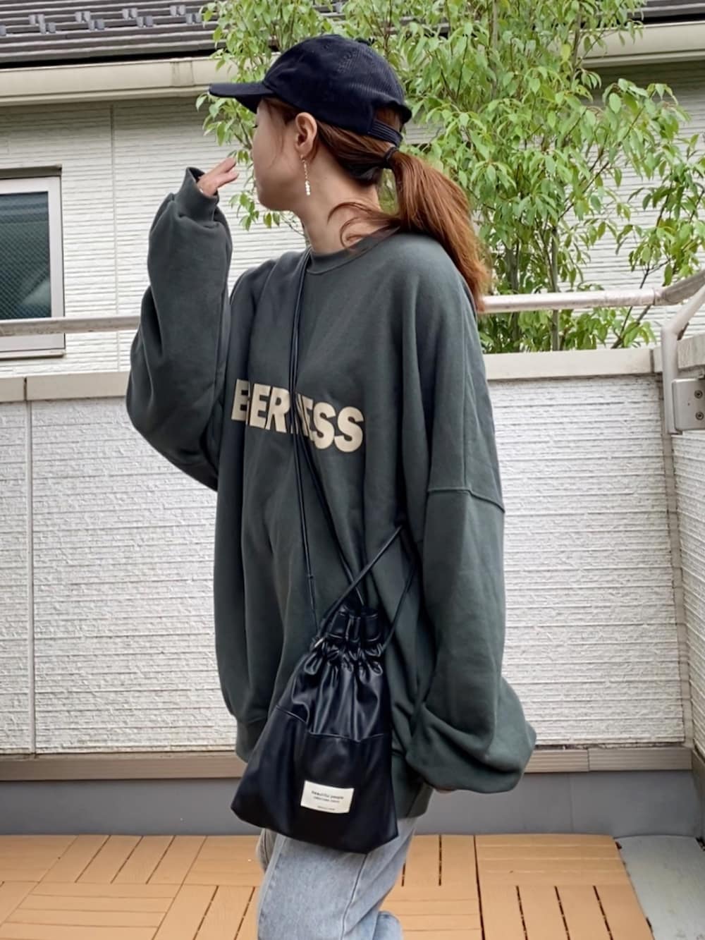 グリーン系のスウェット、ブルー系のデニムパンツ、ブラック系のショルダーバッグを着用したレディースの秋コーディネートの4枚目の写真